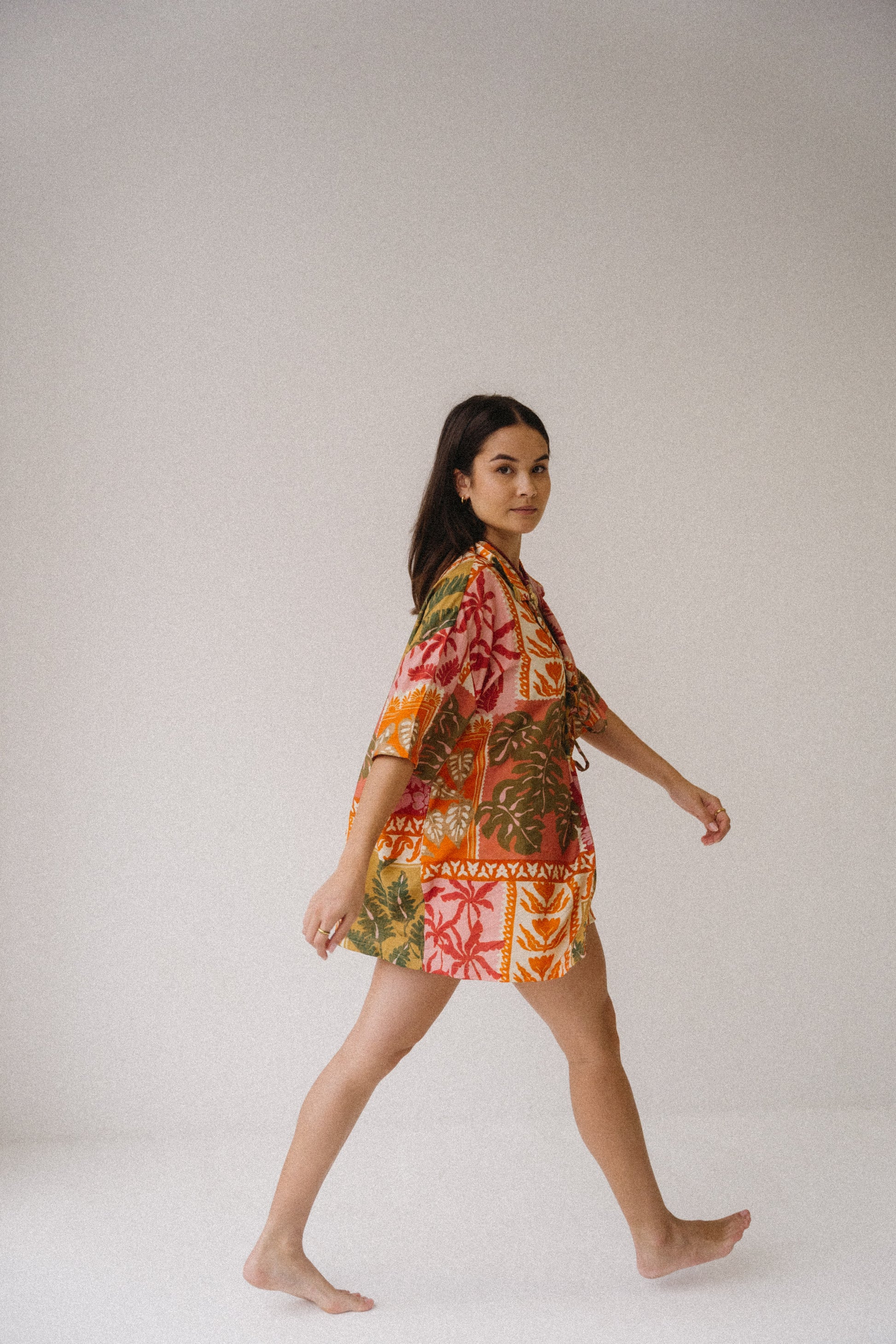 Woman wearing a colorful floral dress on a plain background