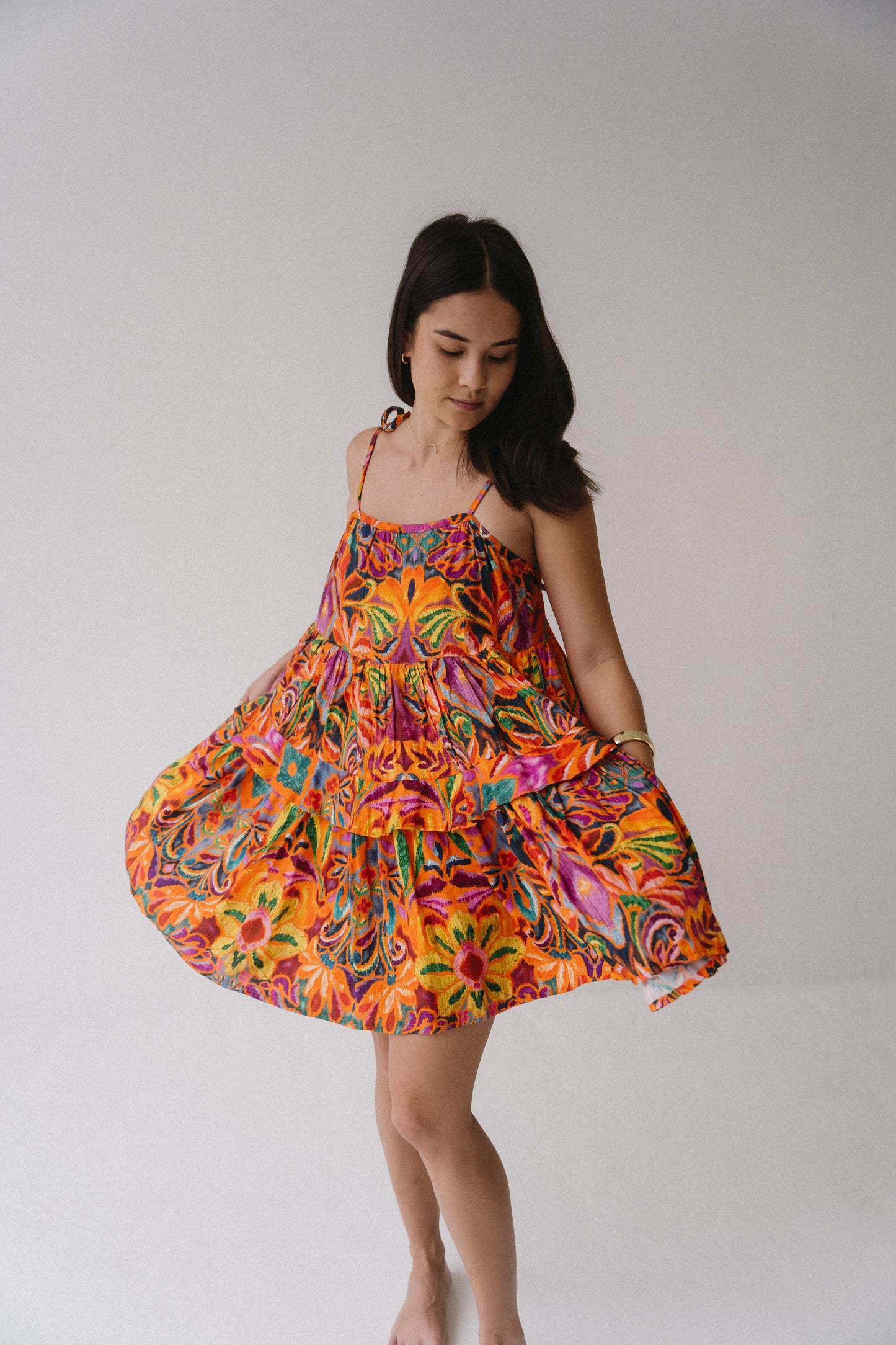 Woman wearing a colorful floral dress against a plain background