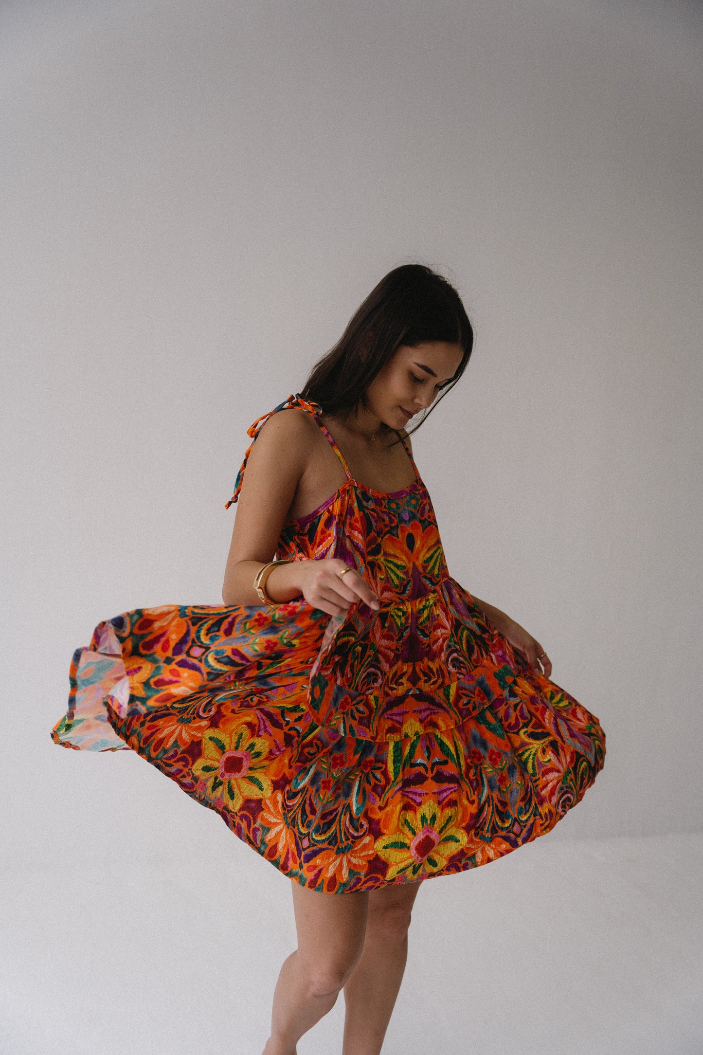 Woman wearing a colorful floral dress against a plain background